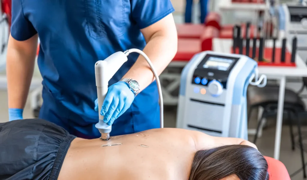 Paciente recibiendo tratamiento de ondas de choque radiales en espalda- clinica de lesiones deportivas