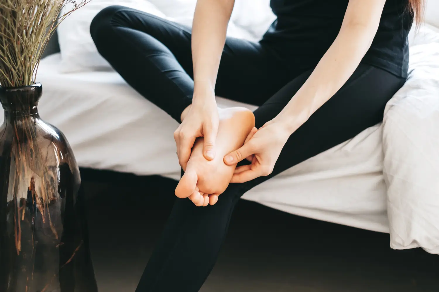 Primer plano de los pies de una persona al levantarse de la cama, con un gráfico de dolor que ilustra el síntoma característico de la fascitis plantar