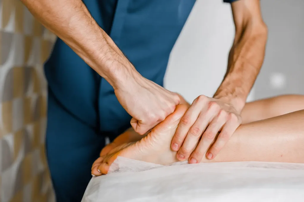 Un fisioterapeuta aplicando terapia manual en el pie de un paciente para tratar la fascitis
